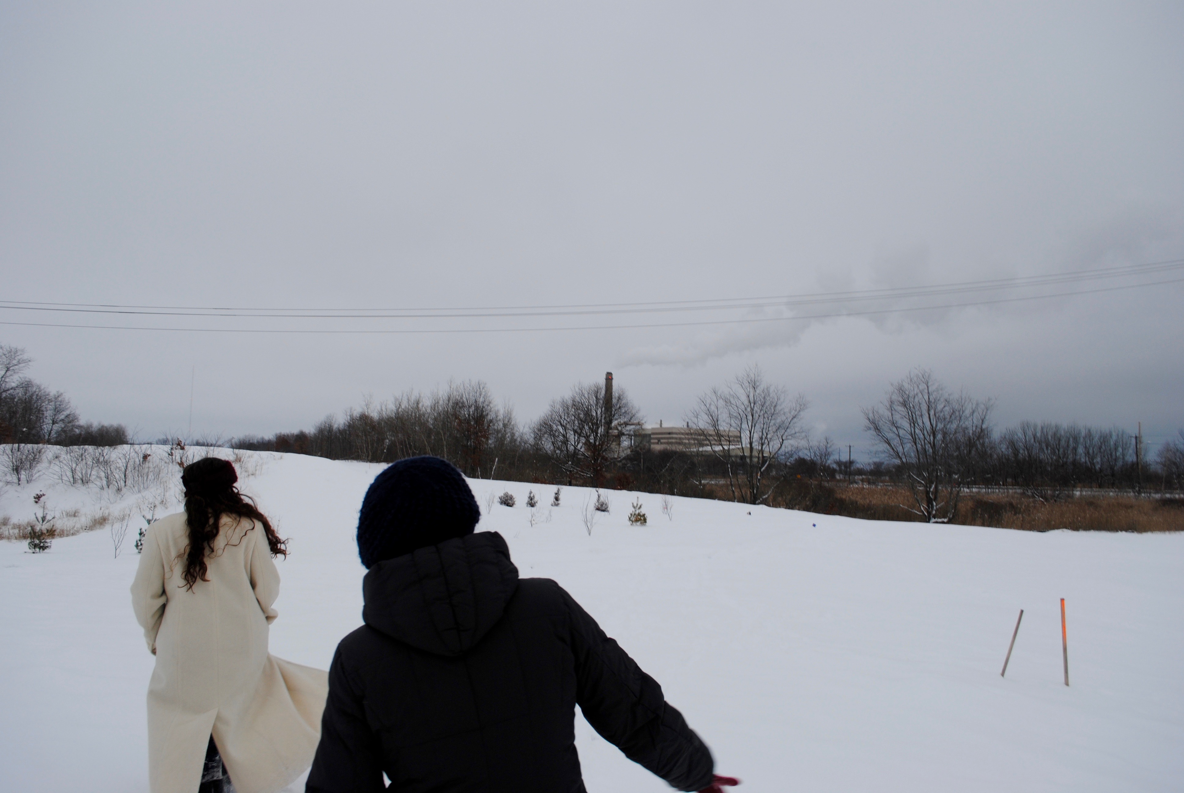 two women walk with the incinerator in the background